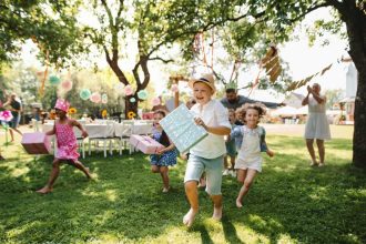 Enfants courant avec des cadeaux lors d'une fête d'anniversaire en plein air